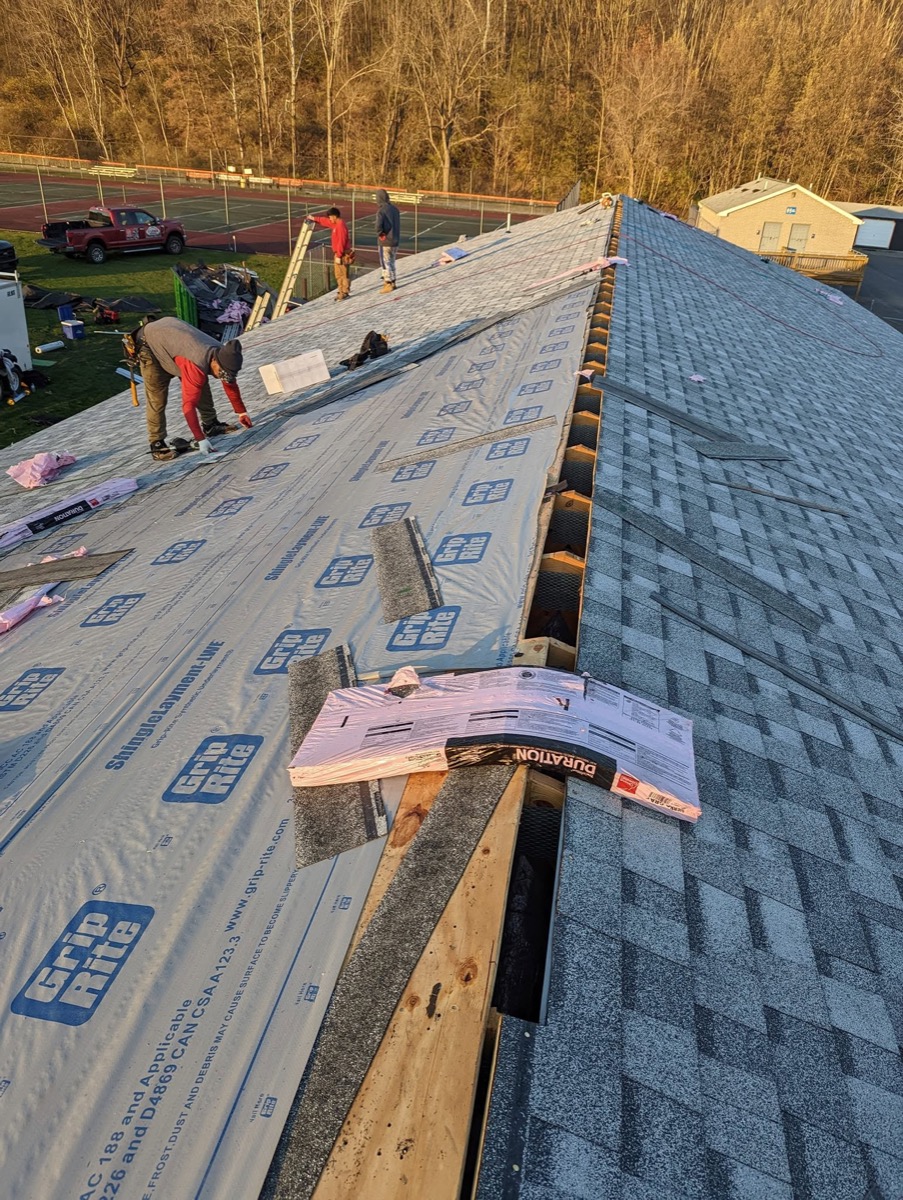 Crew installing synthetic underlayment and Owens Corning Duration shingles at golden hour