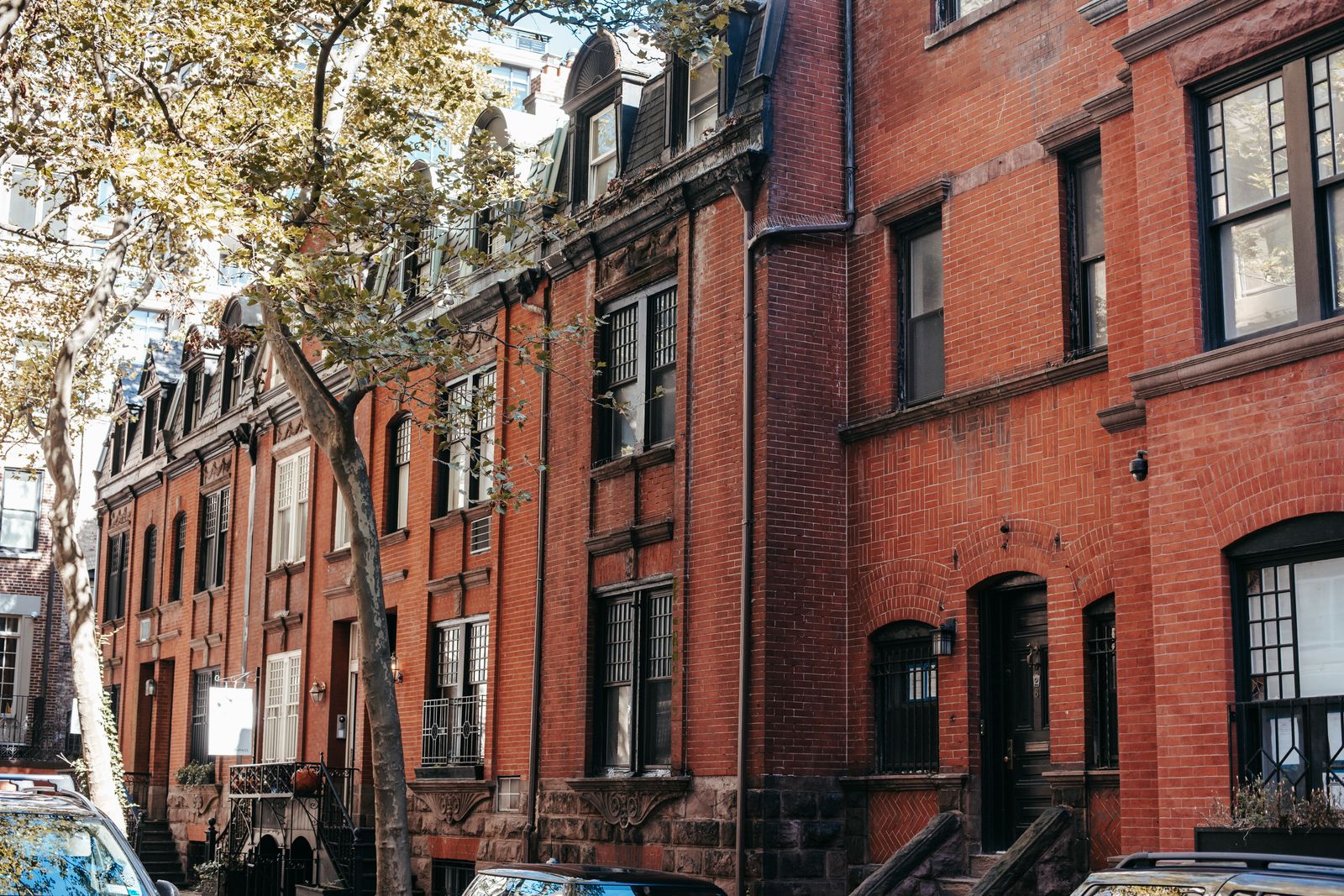 Aged brick residential buildings with front stairs on a sunny city street