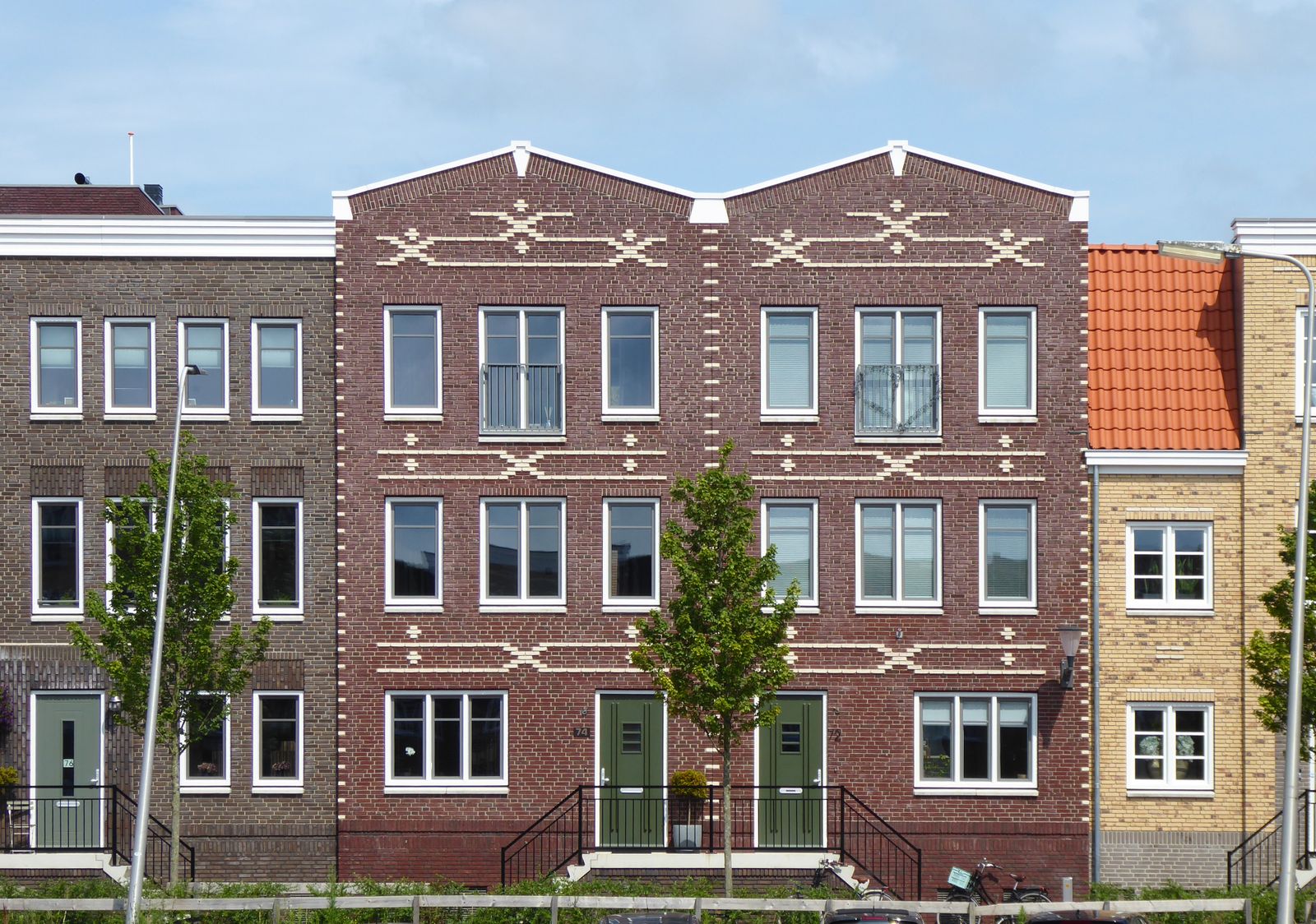 Symmetrical brick rowhomes with shared rooflines on a residential street