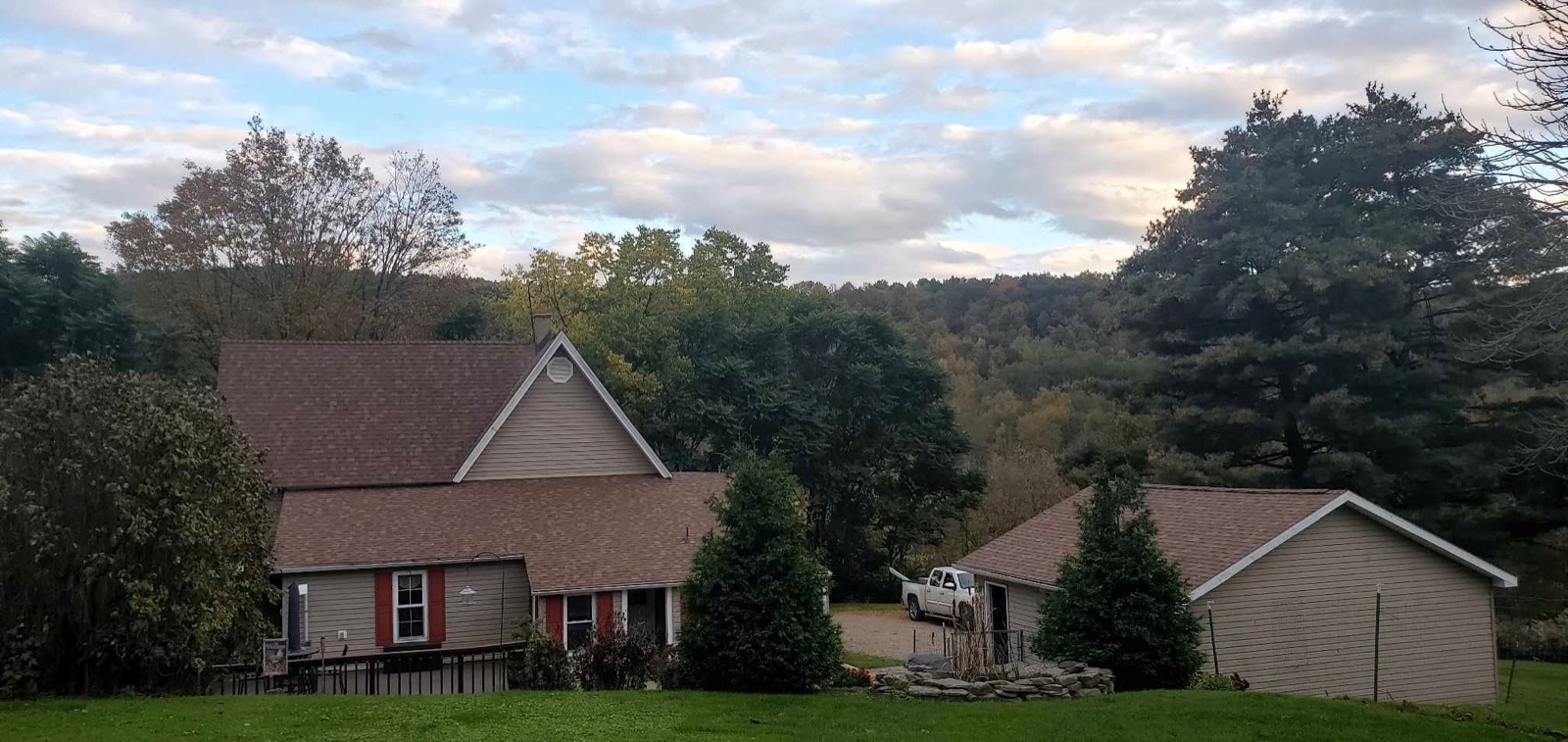 Country home and garage with completed roof replacements under an evening sky