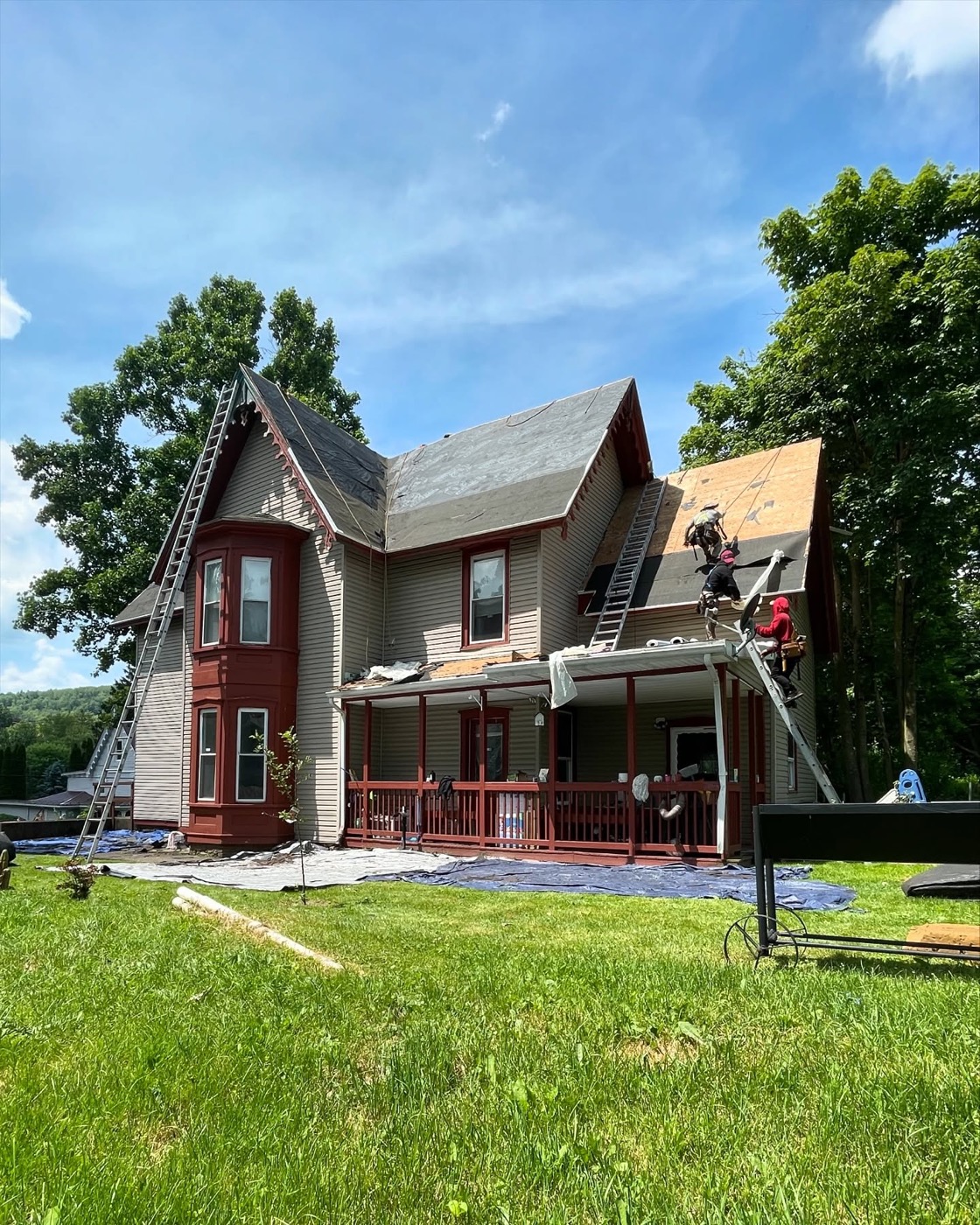 Rail Roofing Group crew tearing off the old roof of a historic home, decking exposed